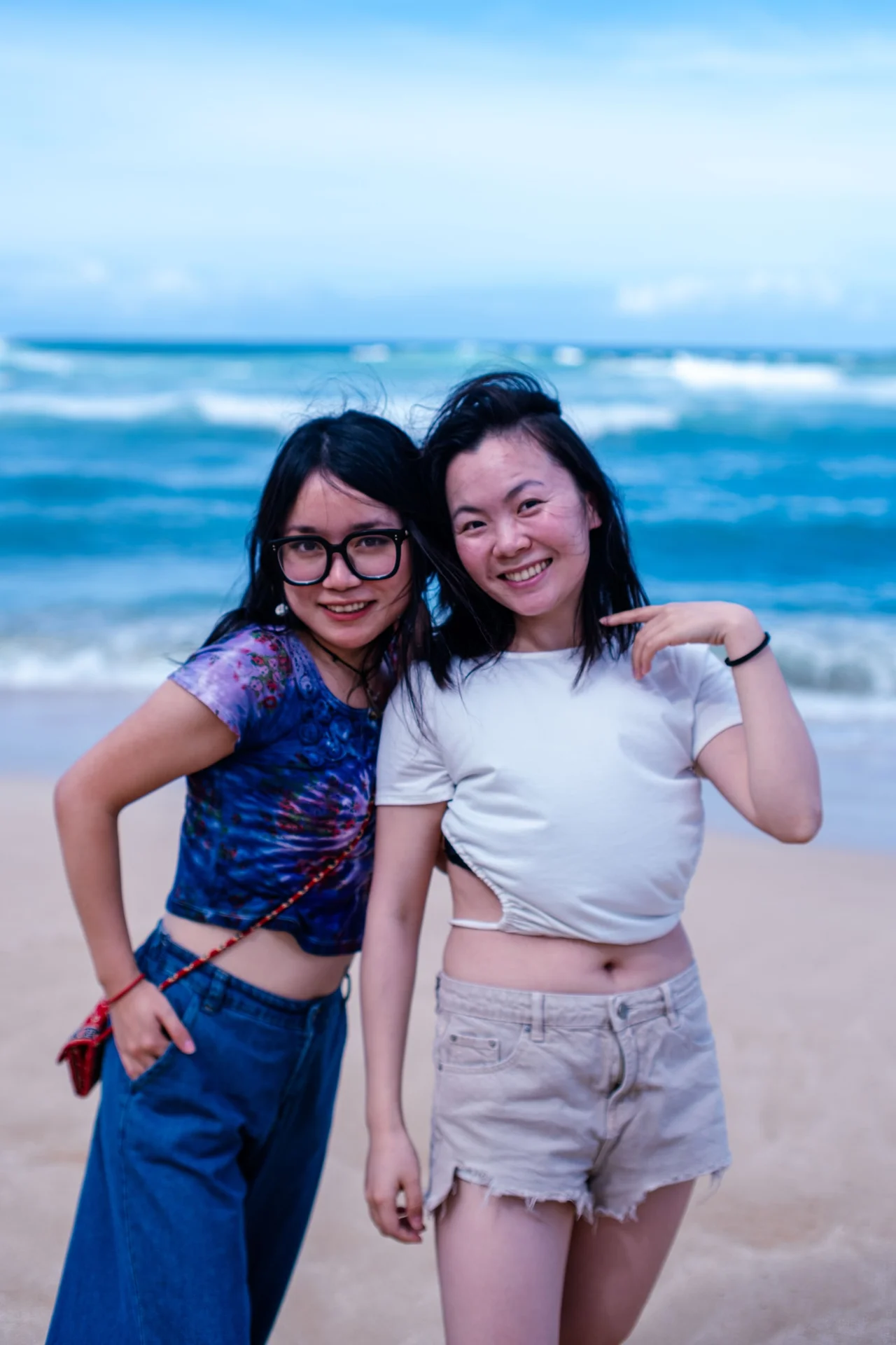Two women smiling together on a beach.
