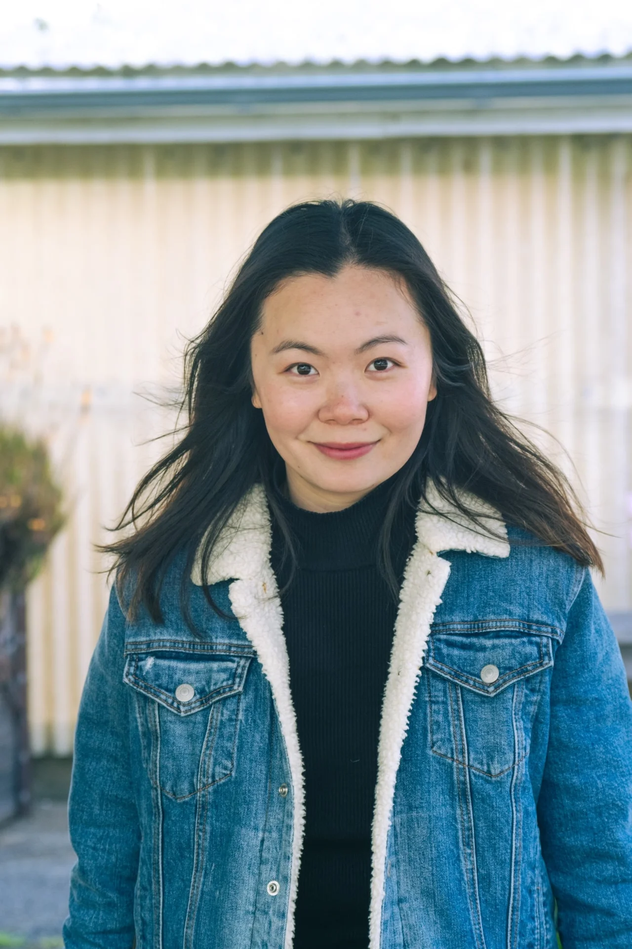 Woman in a denim jacket looking directly at the camera.